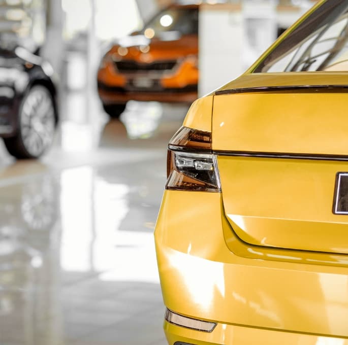 Dealership cars with yellow car in showroom Dark Fade Applied website